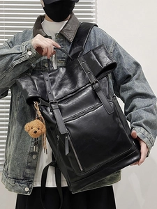 Minimalist black leather roll-top backpack with metal buckles and plush bear charm