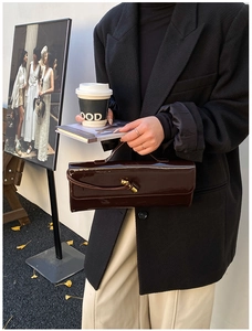 Détail du sac à main en cuir verni marron foncé avec boucle métallique et style urbain