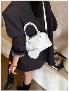 Minimalist white shell bag with heart charm and crossbody strap shown in lifestyle context
