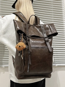 Minimalist brown leather backpack with roll-top buckle design and cute dog charm on the side