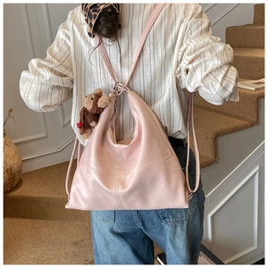 Detail of light pink leather hobo bag featuring contrast stitching and a bear charm