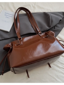 Detail view of dark brown glossy patent leather tote with dual top handles and crinkle texture