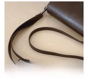 Detail showing the adjustable dark brown leather shoulder strap with silver metal buckles