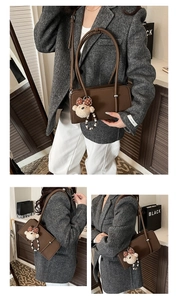 Detail of a dark brown baguette bag with thin handles and a plush bear charm accessory