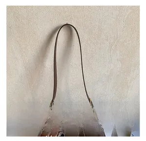 Detail view of coffee leather bag featuring polka dot bow charm and adjustable strap