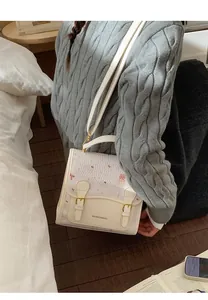Detail of white cartoon bear handbag showing flap design and metal hardware accents
