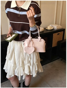Pink glossy patent leather handbag detail featuring a large heart-shaped charm and logo