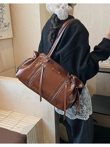 Detailed view of the large brown shoulder bag with shiny finish and silver zippers