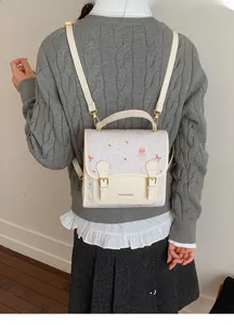 Detailed back view of a beige school-style backpack with cute cartoon bear and cupcake prints