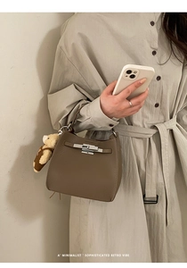 Detail of dark khaki pebble leather bucket bag with silver twist lock and plush bear charm
