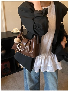 Detail of dark brown vintage shoulder bag with golden hardware and fuzzy charm