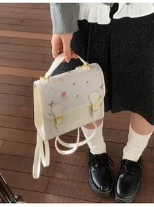 Detail of cream white handbag with cartoon cat prints and metallic buckle closure