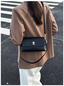 Detailed back view of a black leather crossbody bag featuring a silver twist-lock closure