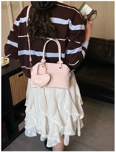 Pink heart-decorated handbag displayed in a stylish indoor lifestyle setting for women
