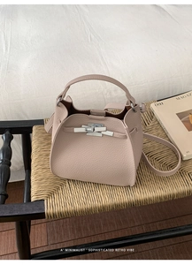 Detail of lychee pattern leather bucket bag with silver twist lock on a woven stool