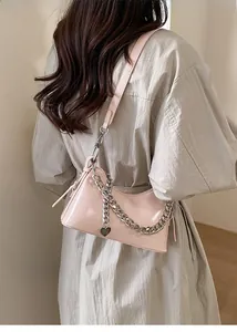 Detailed view of pink glossy faux leather shoulder bag with thick metal chain and heart charm