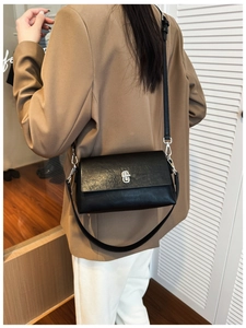 Detail view of black lychee grain leather crossbody bag with silver rotating metal lock