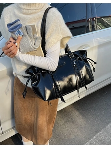 Detailed view of black high-gloss PU leather tote bag with drawstring and metal zipper