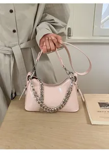 Detail view of pink glossy leather handbag with silver chain and metal zipper closure