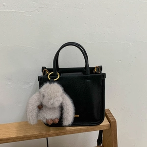 Détail d'un sac seau noir avec garnitures dorées et un charmant lapin en peluche