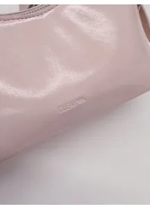 Detailed macro view of the embossed logo on the light pink textured leather handbag