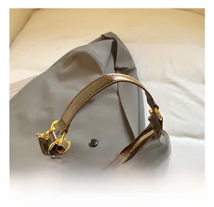 Détail du sac à bandoulière marron foncé brillant avec ferrures dorées et sangle