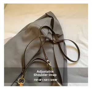 Détail d'une bandoulière en cuir réglable avec boucles dorées sur un sac à main gris