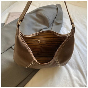 Dettaglio borsa hobo in pelle scamosciata marrone con fodera a righe e borchie dorate