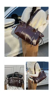 Detail of dark brown wax leather tote bag featuring fringe zippers and drawstring design