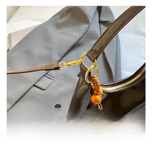 Gros plan d'un sac en cuir brillant marron foncé avec crochets dorés et anneau en D