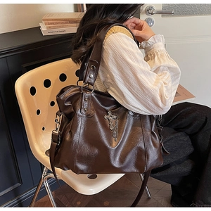 Detail of vintage brown PU leather tote with silver cross pendant and metal chain