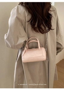 Pink waxed leather Boston bag with metallic chain strap shown on model's shoulder