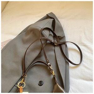 Detail of dark brown leather shoulder bag with gold rings and a woven tassel charm