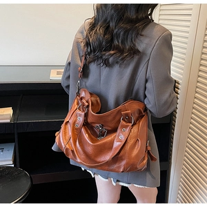 Detail shot of large brown leather tote bag featuring a silver cross star buckle