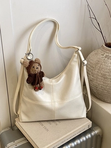 Minimalist off-white hobo tote bag with cross-stitch and brown bear pendant accessory