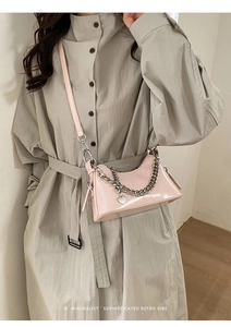 Close-up of pink patent leather handbag with silver chain and heart charm detail