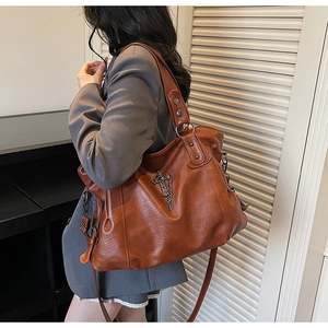 Detailed macro of vintage caramel leather tote with metallic cross chain and studs