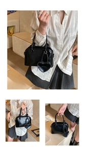 Macro detail of black glossy leather shell bag with knot handle and heart charm