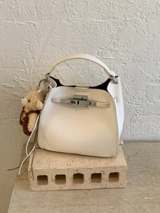 Cream lychee textured bucket bag with silver buckle and cute teddy bear charm on stone
