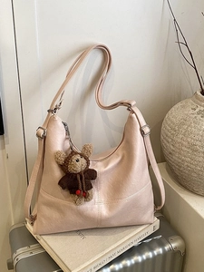 Beige large capacity Hobo tote bag with a cute bear pendant on a silver suitcase