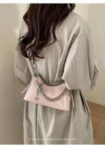 Close-up of pink patent leather bag featuring a chunky silver chain and heart pendant