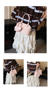 Detail view of pink square handbag with dual ring handles and heart charm accessory