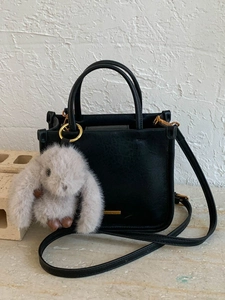 Sac seau noir minimaliste avec détails dorés et charmant pendentif lapin en peluche