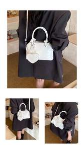 Detail of white glossy shell bag with heart charm and adjustable shoulder strap