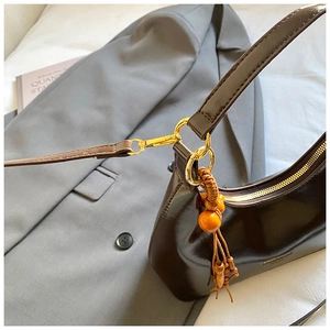 Close-up of brown leather hobo bag with golden hardware and colorful beaded tassel