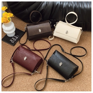Detail view of four minimalist square crossbody bags in brown, beige, red, and black leather
