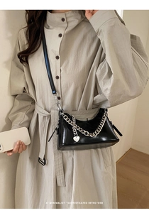 Close-up of retro black oil wax leather bag with bold silver chain and heart pendant