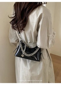 Detail of black wax leather shoulder bag with bold silver chain and heart charm