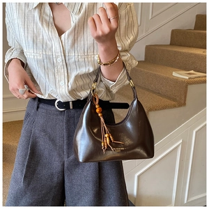 Detail of dark brown glossy leather hobo bag with wooden bead tassel and brand logo