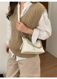 Detail of cream leather bag with silver chunky chain and heart charm on a model